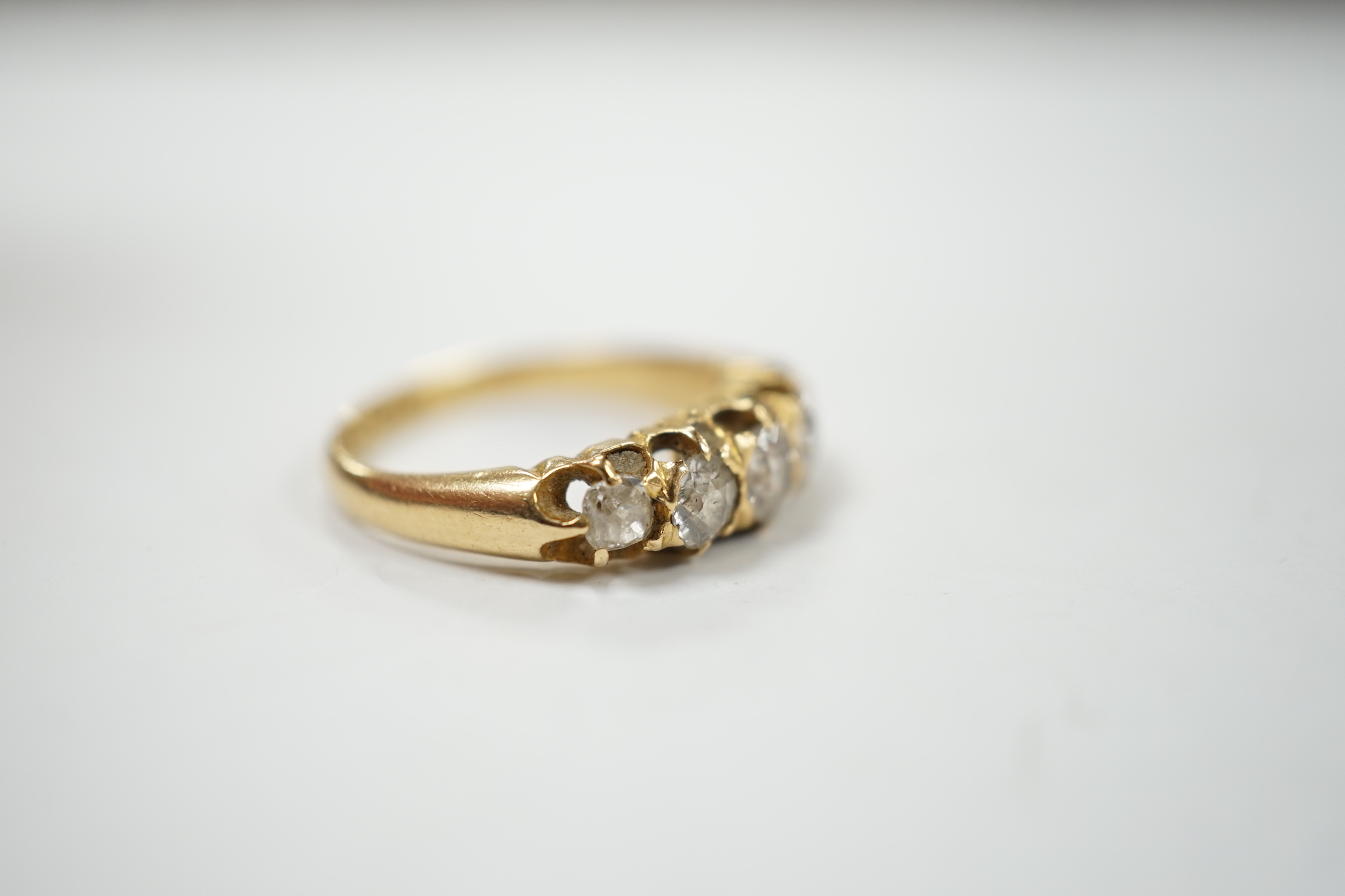A late Victorian 18ct gold and graduated five stone diamond set half hoop ring, size L/M, gross weight 3.6 grams.